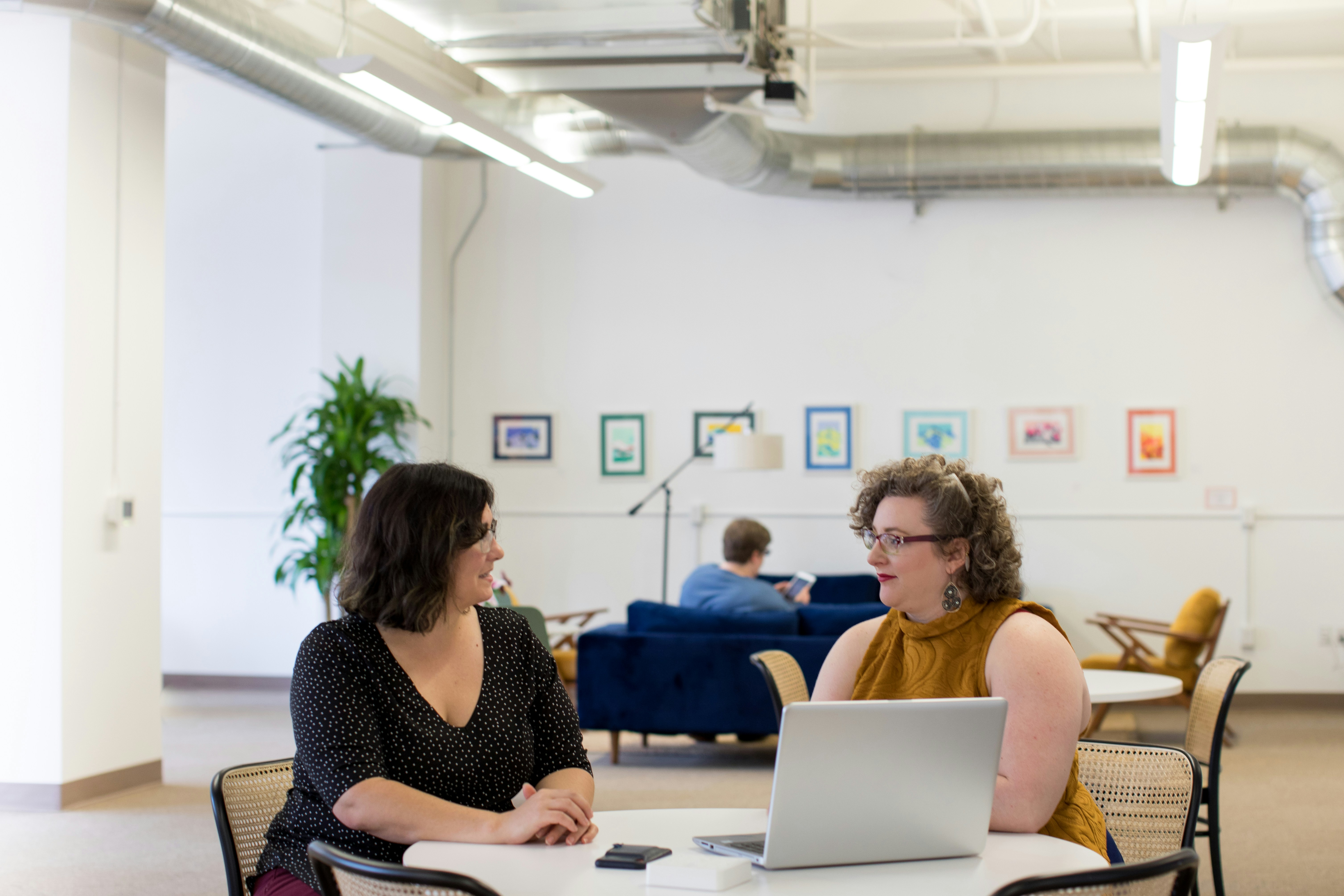 Two people chatting at a table with a laptop in front of them
