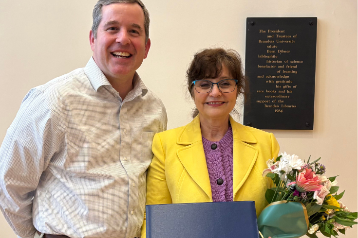 Dr. Anna Shebanow standing next to Assistant Dean of Education and Learning Innovation Scott Stanley, holding flowers and an award in her hands