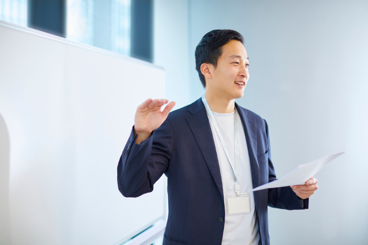 Person giving a presentation at the front of a conference room