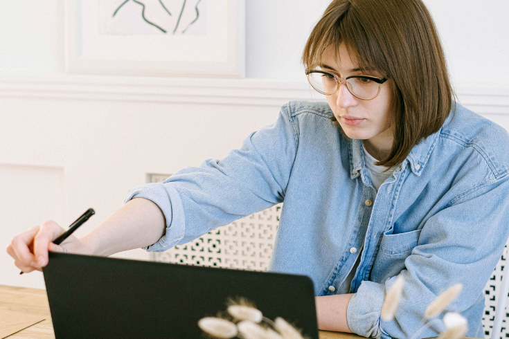 Person looking at laptop screen with a pencil in hand