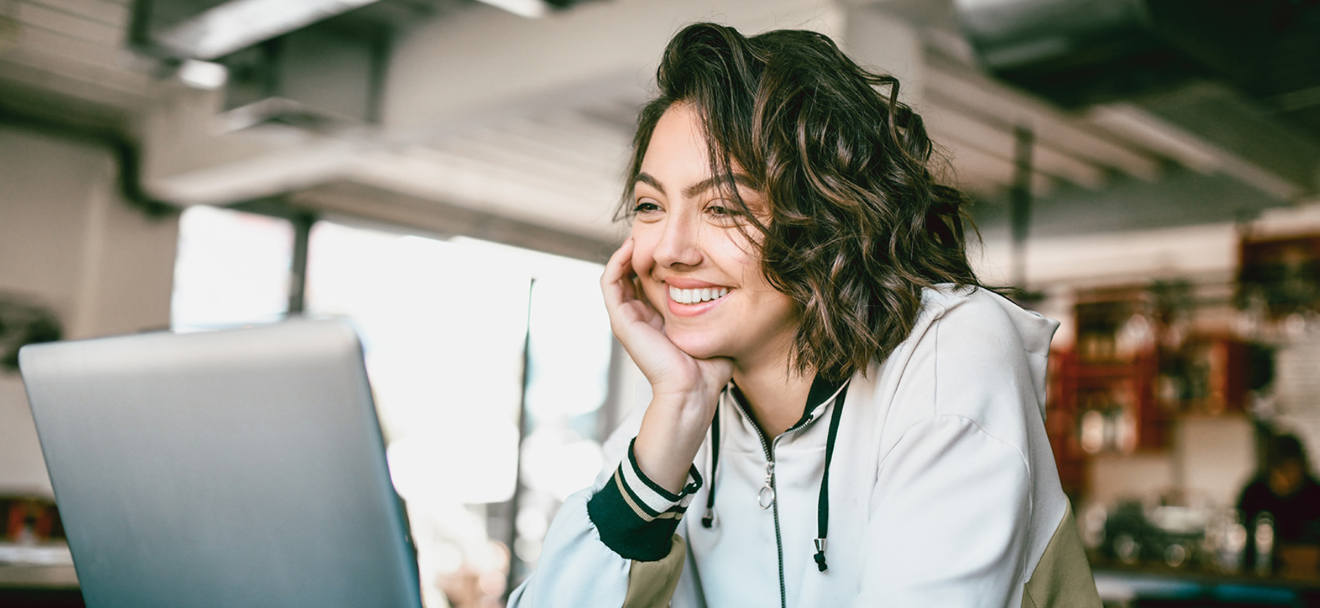 A person smiles while looking at a laptop