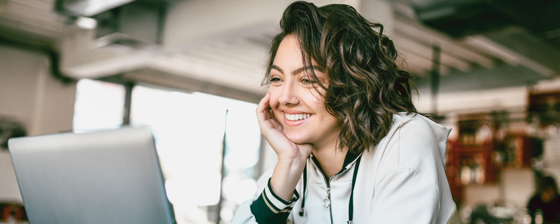 Woman using the computer, looking happily into the distance.