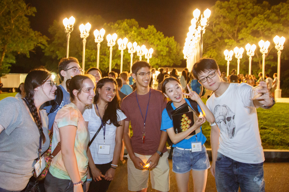 Students standing at the Light of Reason at night