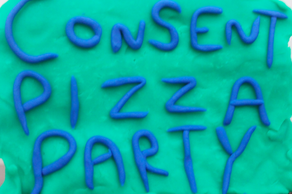 sign reading Consent Pizza Party being held by a claymation blue dinosaur