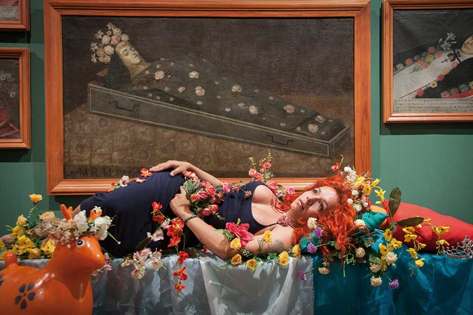 art installation - woman in a coffin covered with flowers