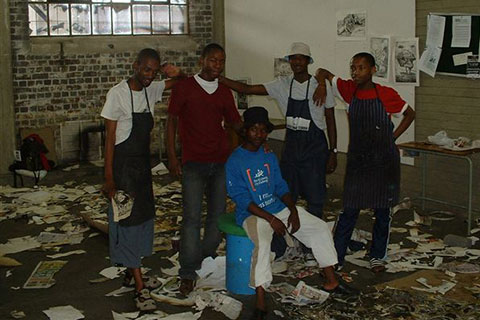 People pose for a photo in the middle of a messy room