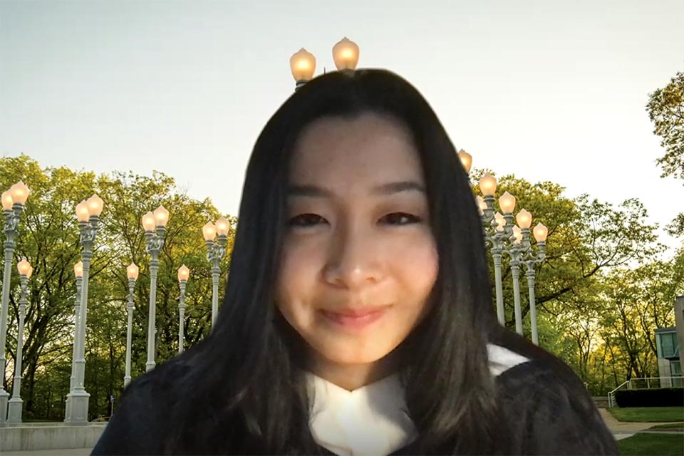 Screenshot of Jessica Wei delivering her speech via Zoom with the Light of Reason sculpture as the virtual background image