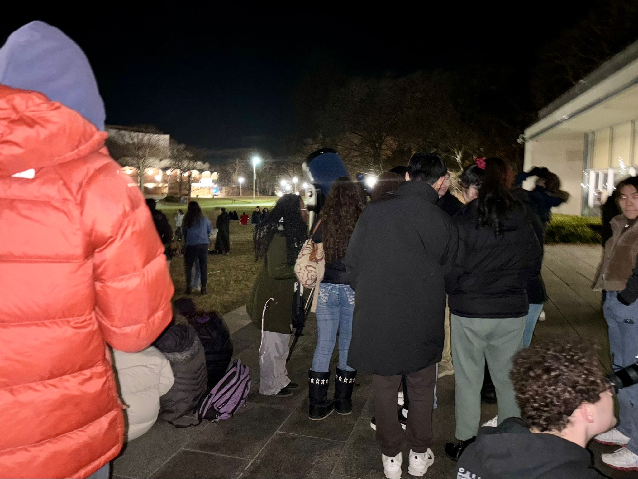 Students gathered around telescopes outside at night.