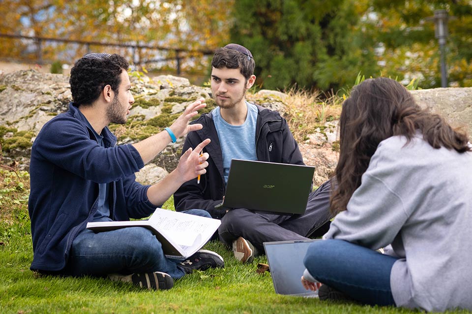 Students sitting on the grass on the Brandeis campus, engaged in discussion