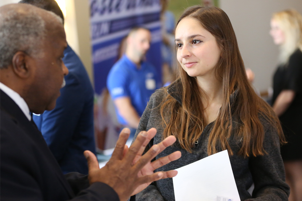 A student speaks with an employer at a career development event.