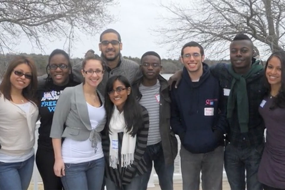 A group of students smiling, standing outside on a gray day