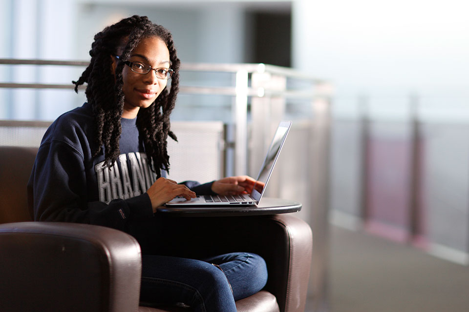 Joelle Robinson sits in a chair with a computer