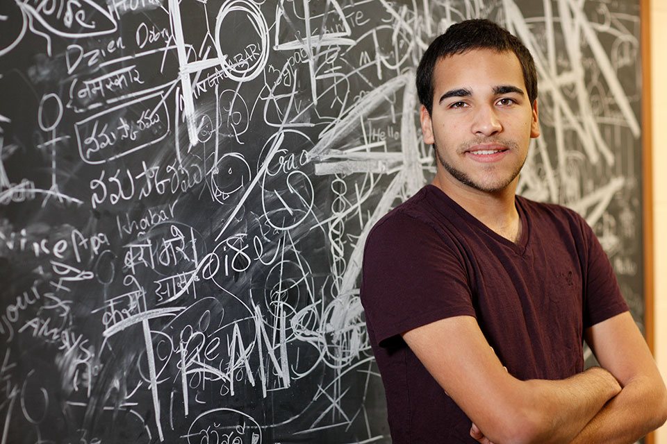 Jose Vargus stands in front of a chalkboard that has been written on.