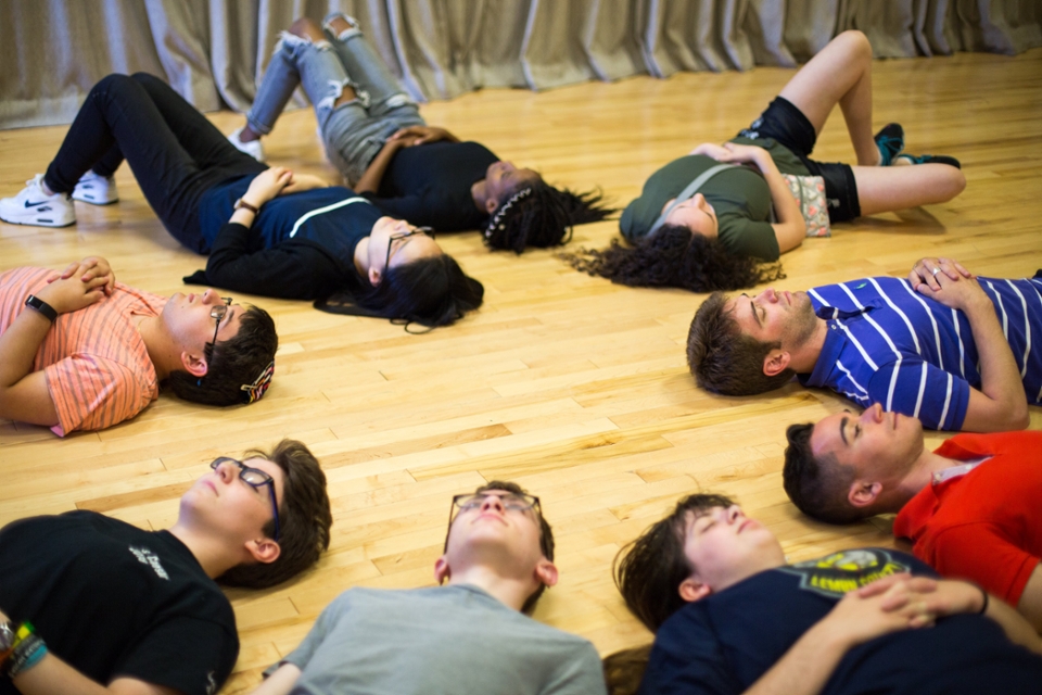 Students relaxing in a circle pattern on the floor.