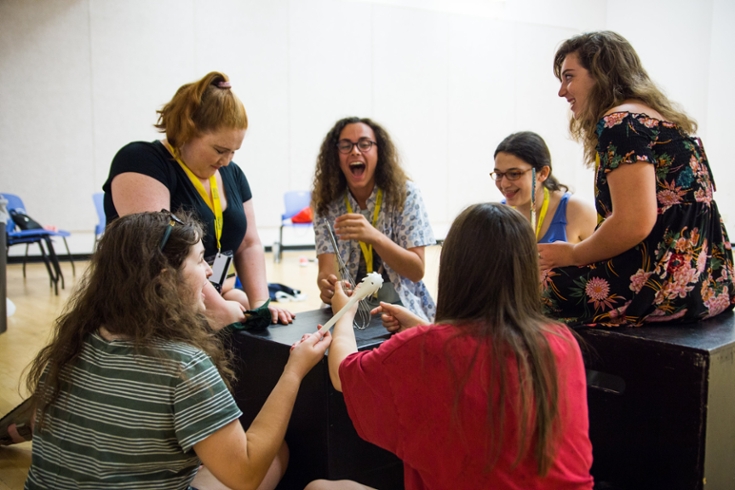 Brandeis Precollege students sitting around a piano and laughing together