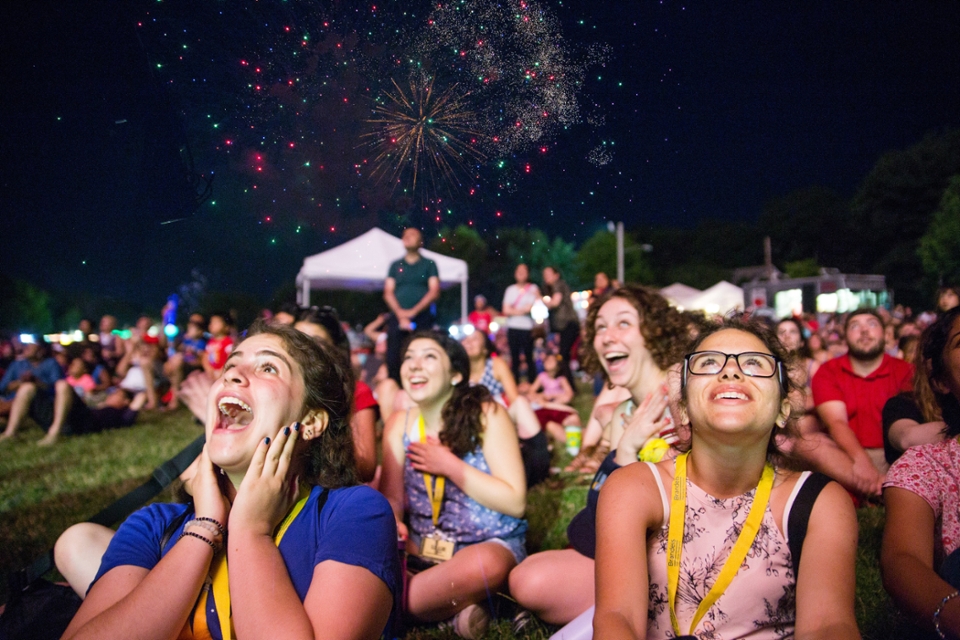 Brandeis Precollege students sit outside at night and watch fireworks with excitement.