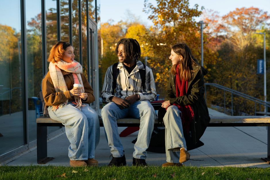 students sit outside on bench