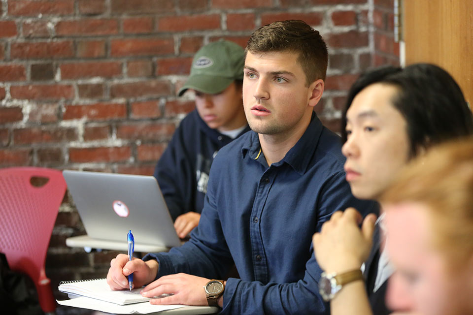 Students seated in a classroom in front of a brick wall during a psychology class