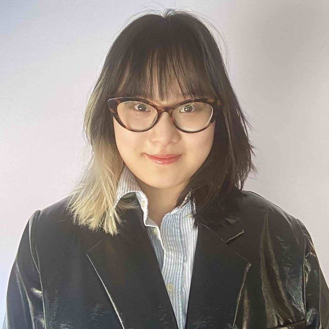 Asian Woman with dark hair and a Blonde peekaboo wearing glasses and a leather coat
