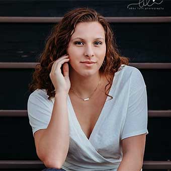 Girl with brown curly hair in a white shirt and jeans
