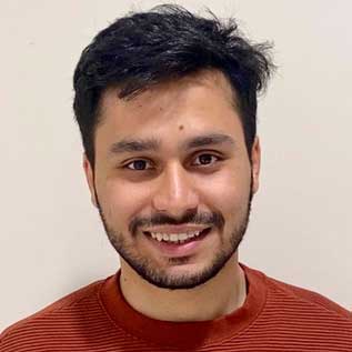 picture of a young man with dark hair and facial hair smiling.
