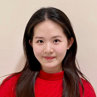 a picture of a young girl with dark hair smiling wearing a red shirt. 