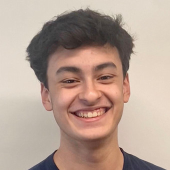 a headshot of a young man with dark hair smiling with a blank background