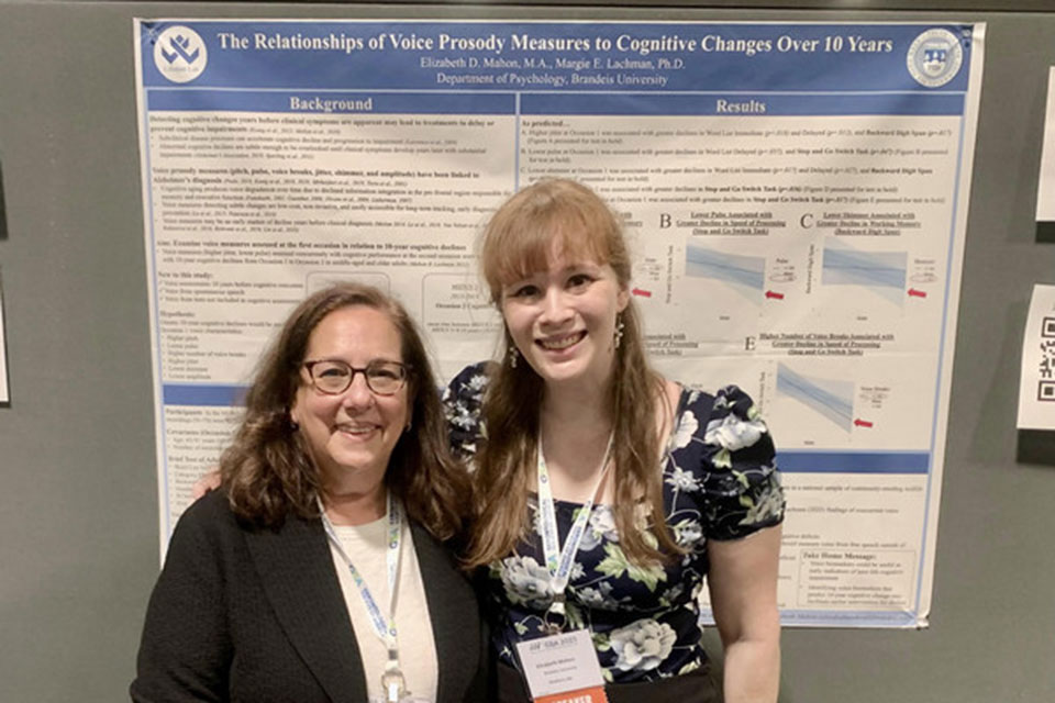 Two lab members stand in front of a research poster.