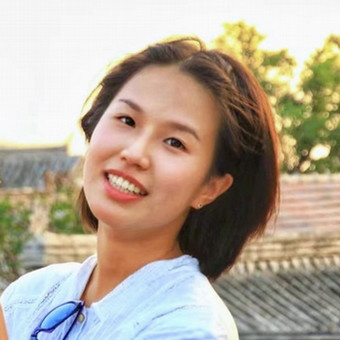 a picture of a young girl with short dark hair smiling with some trees in the background.