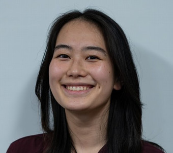 a young girl with dark hair smiling.