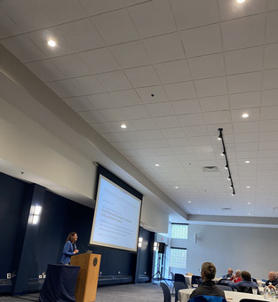 Dr.  Berry standing infront an audience giving a talk.