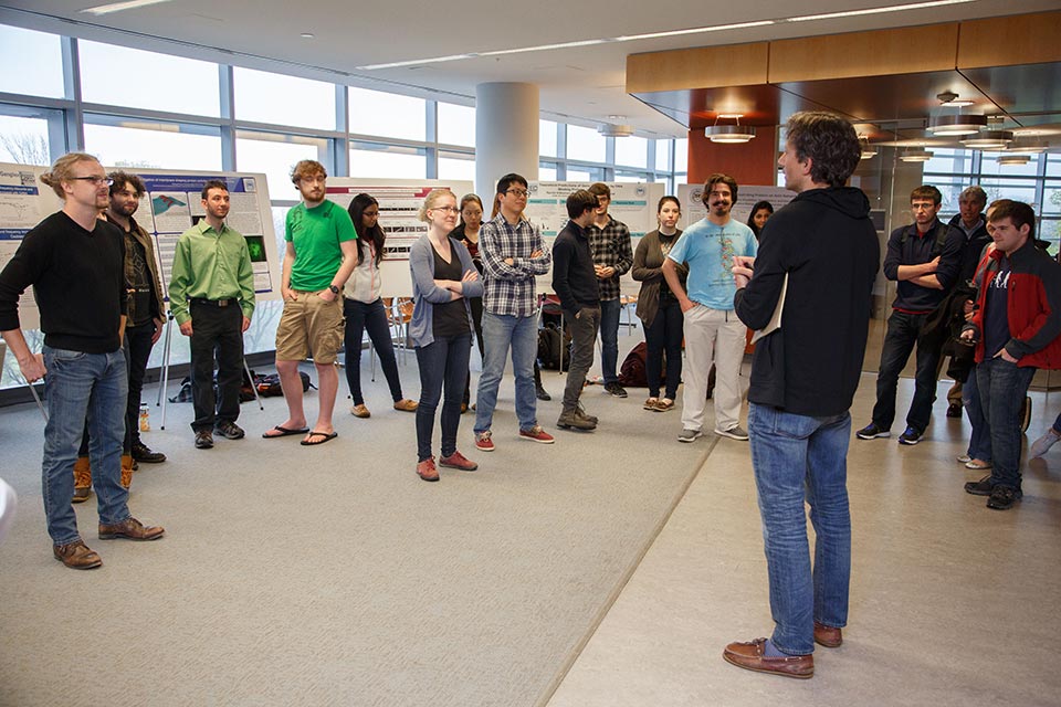 Lab members standing and talking with Jane Kondev, Professor of Physics