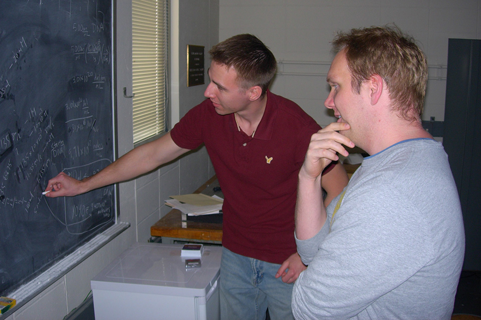 Two QB grad students working at the blackboard