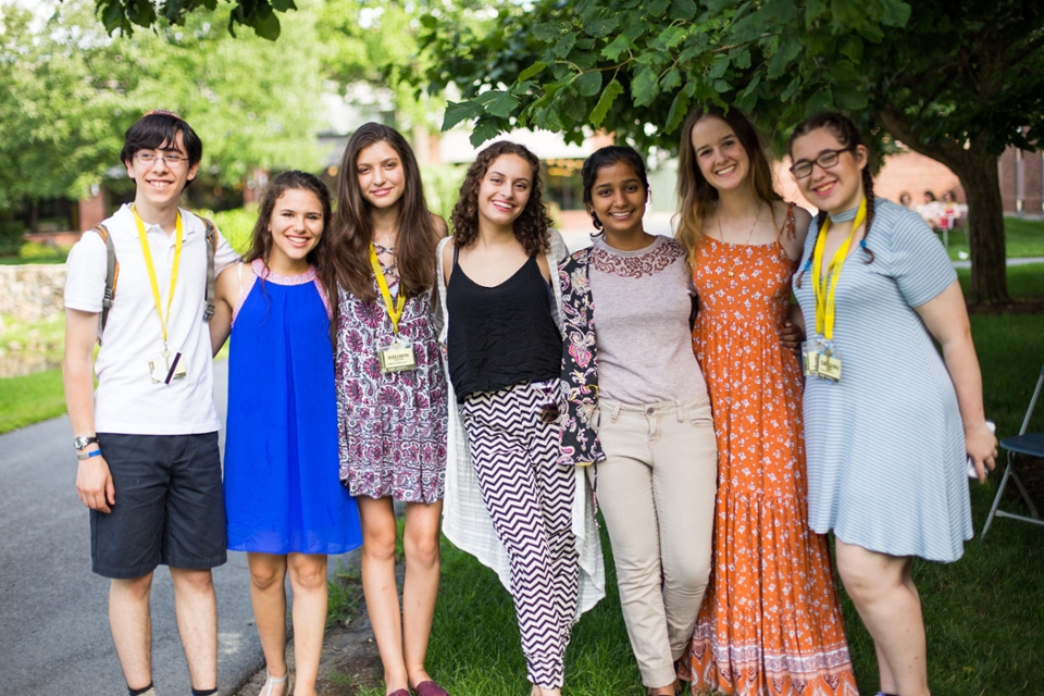 Students stand in a line smiling at the camera