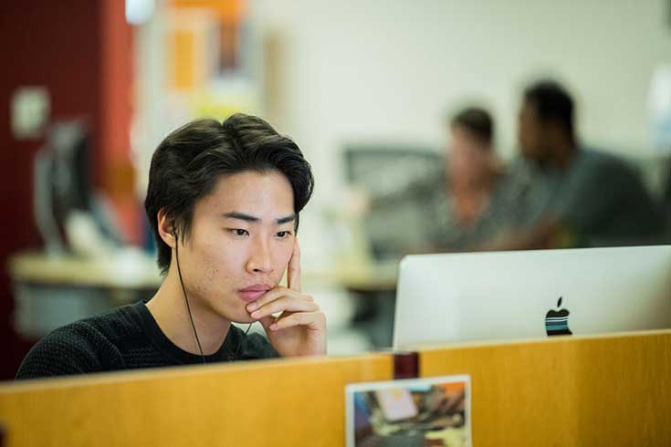 A student sits and looks at a computer