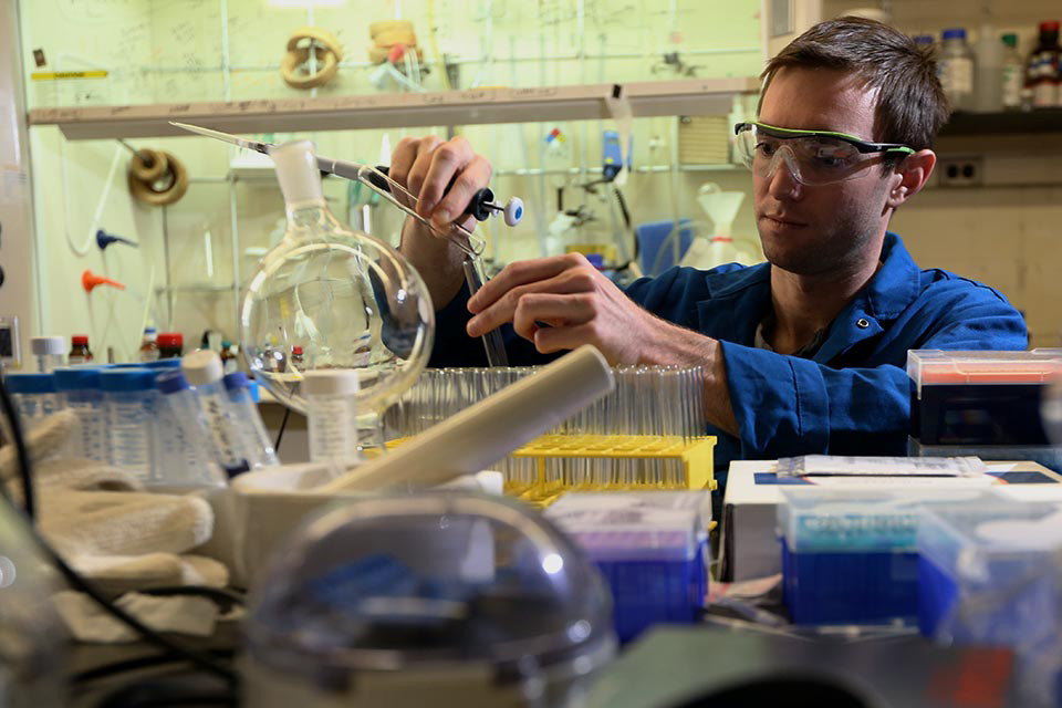 male student conducting a science experiment in lab with test tubes