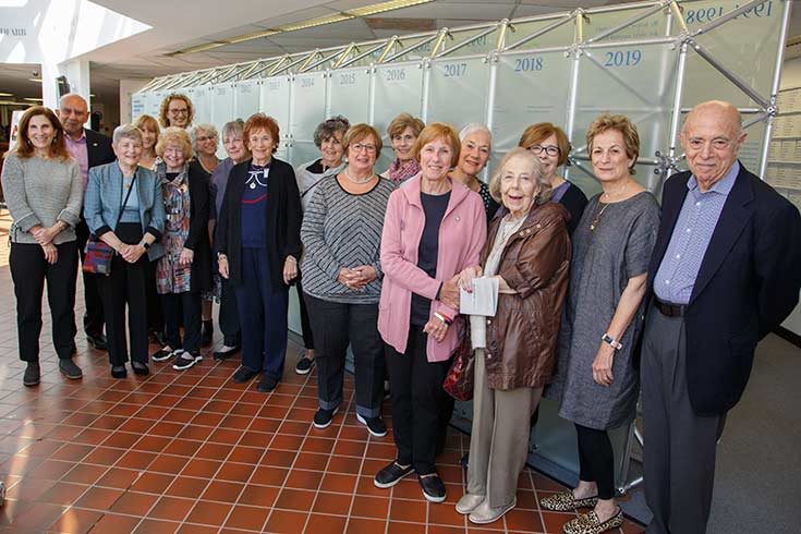 Group of people standing near a dedication wall in the Brandeis Library