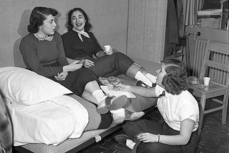 Black and white photo of three people in a residence hall
