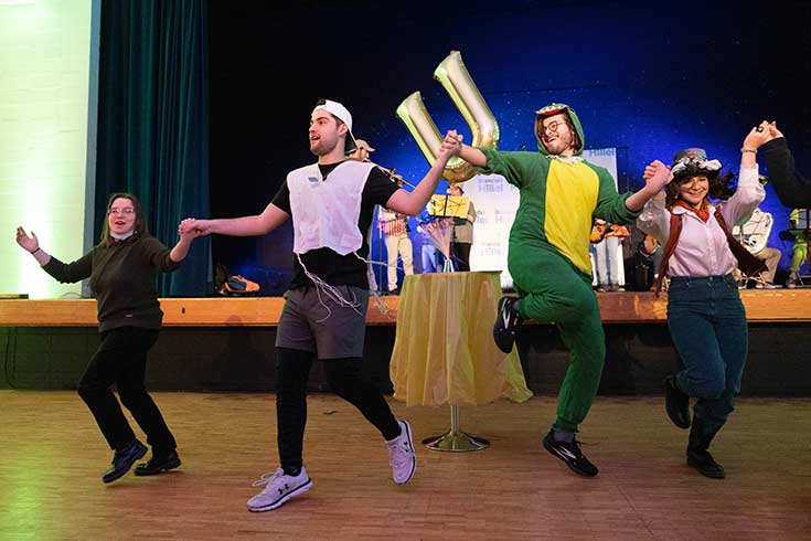 Colorful photo of people celebrating Purim in costumes while dancing
