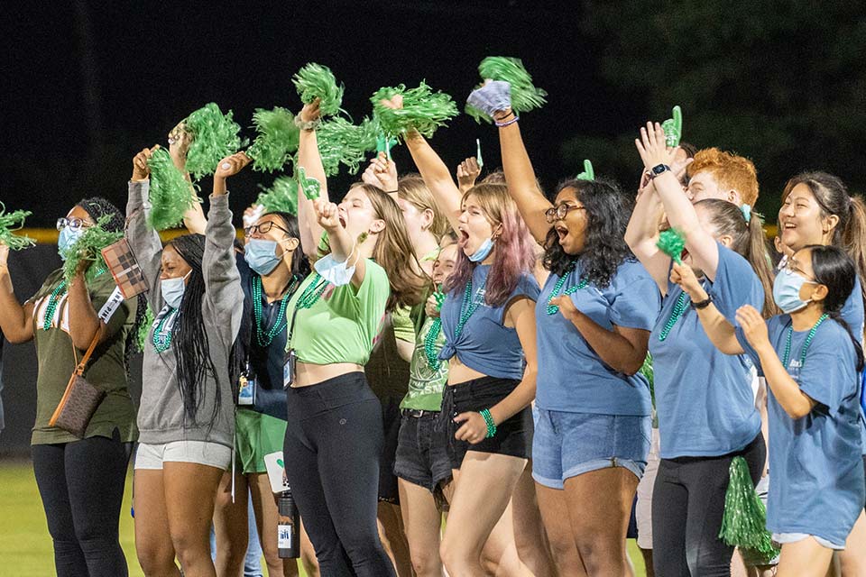 Students in green shirts cheer each other on while playing games on a field