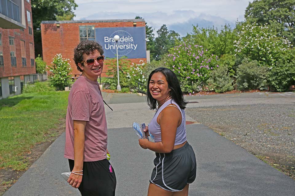 Two students smile while walking around campus