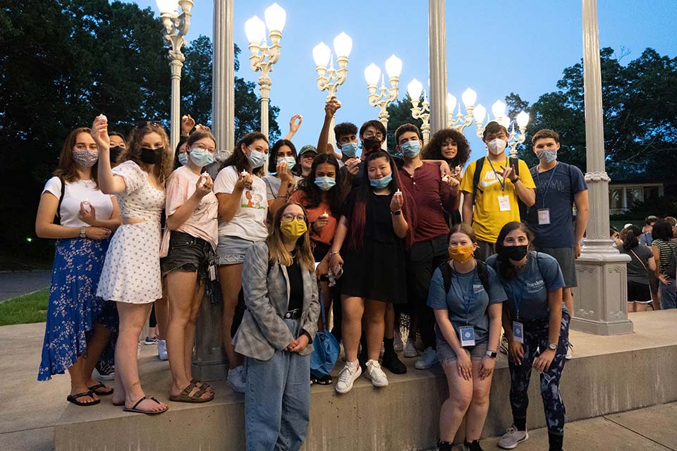 Students pose by the Light of Reason in 2021, many are wearing masks.