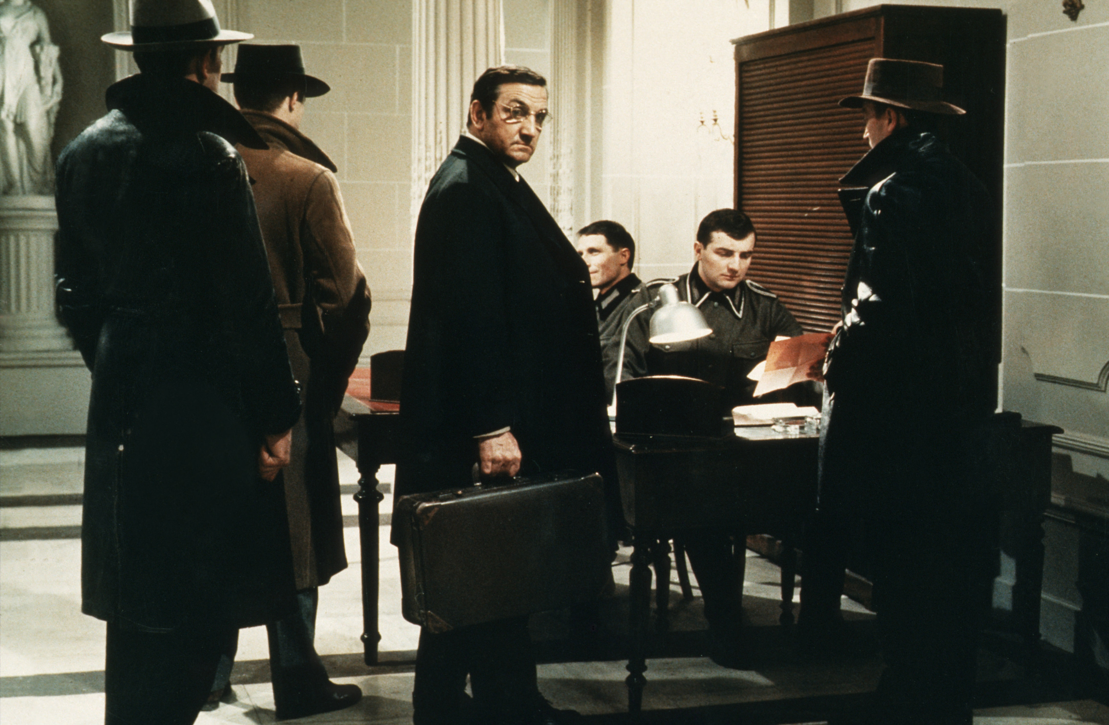 man with a briefcase standing in front of a solider at a desk