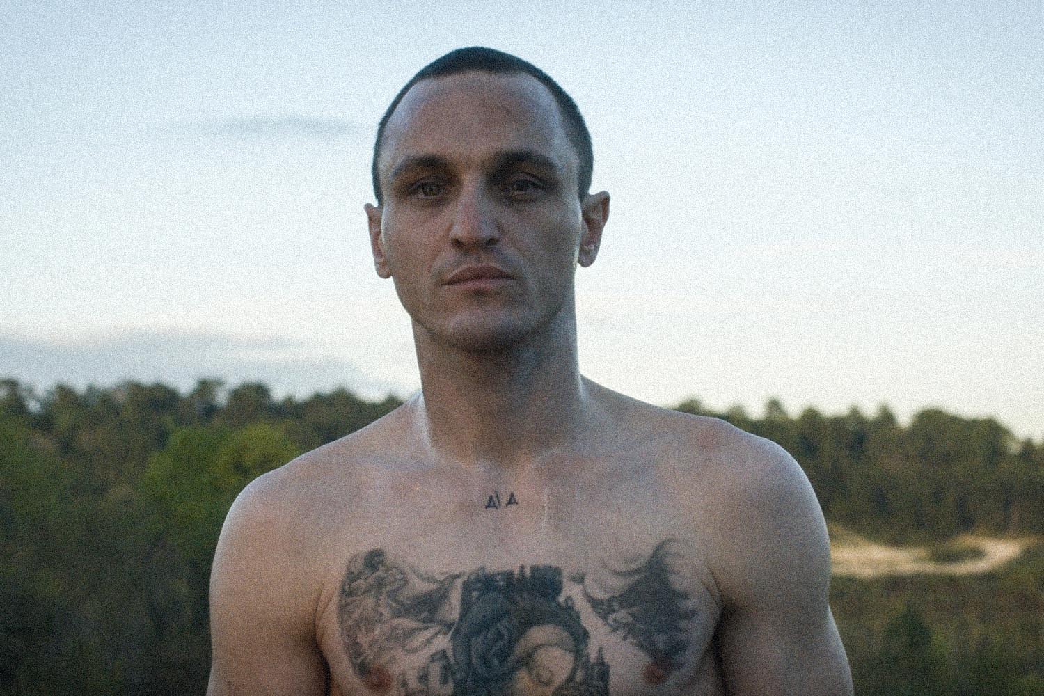 shirtless man with tatoos, standing against sky