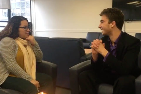 A male student and female student both sit on chairs talking to each other