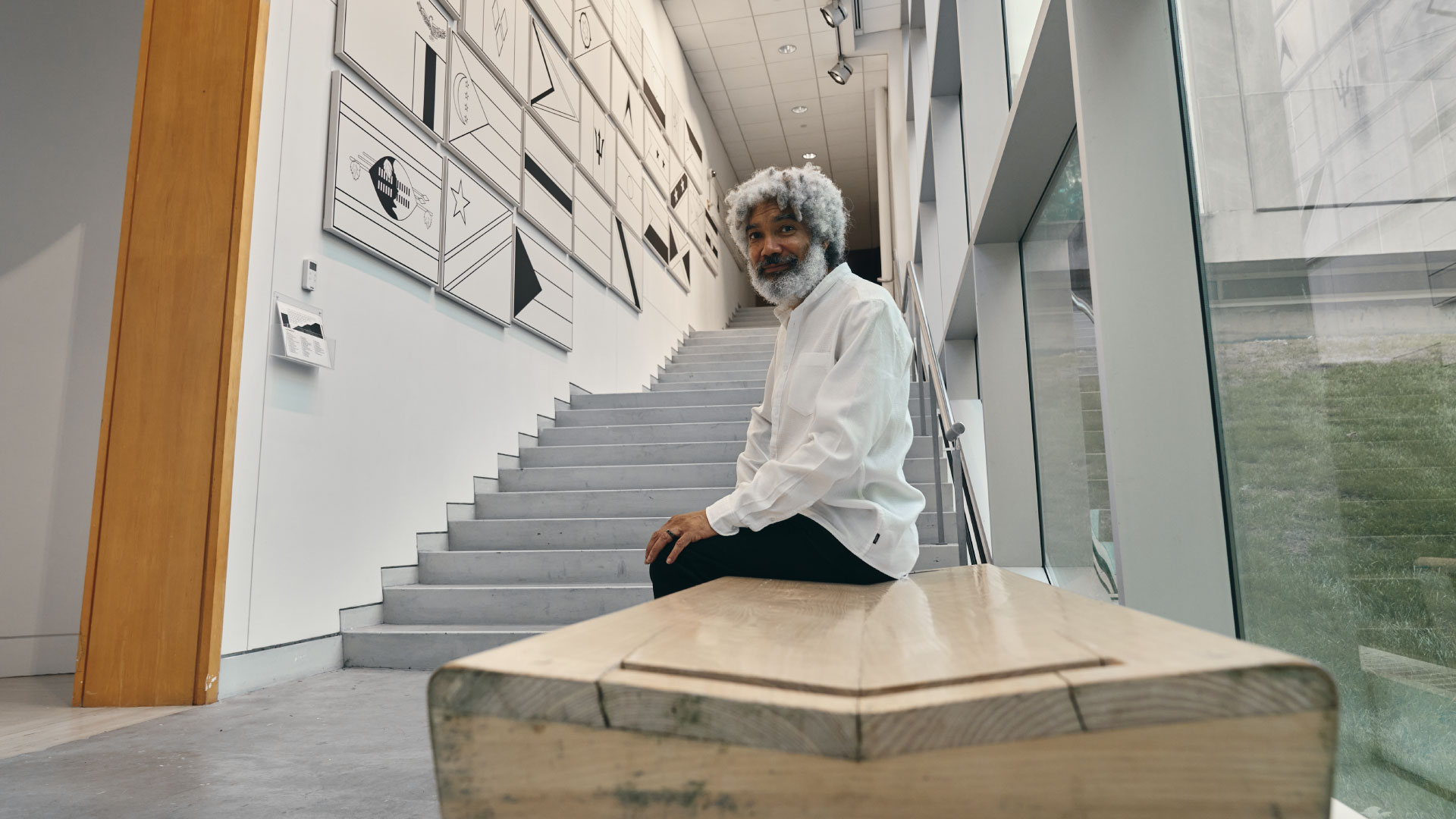 Artist Fred Wilson sitting on a bench in the stairwell of the Lois Foster Wing.