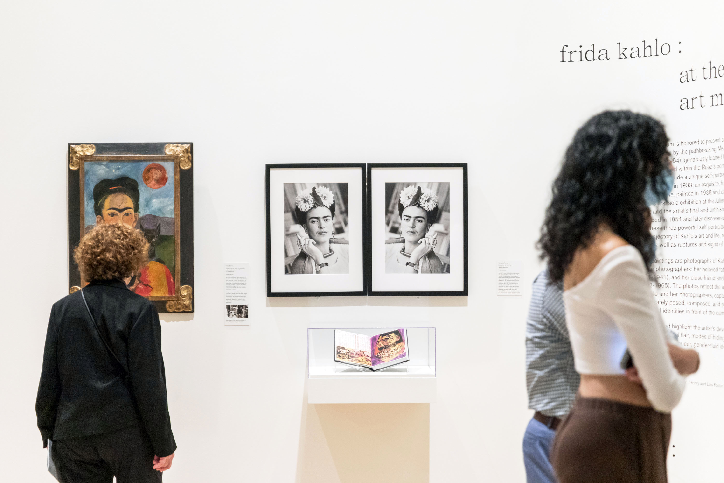 People looking at paintings by Frida Kahlo