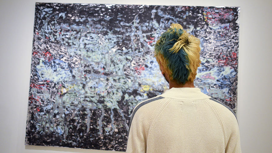 A student standing in front of a painting
