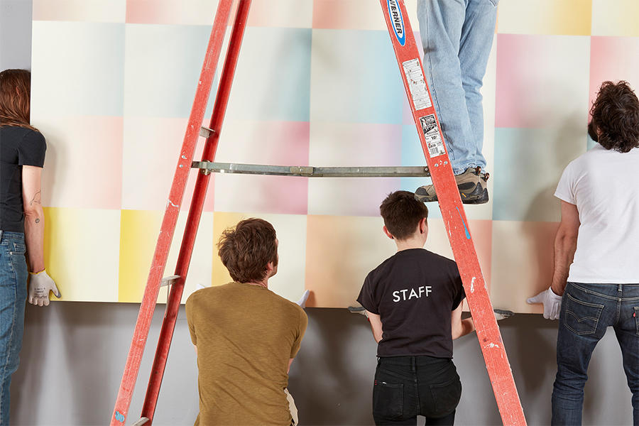 Rose Art Museum staff hang a painting on the wall