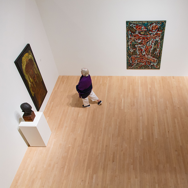 An installation view of Rose exhibition Passage with two paintings and one sculpture. A woman looks at one of the paintings